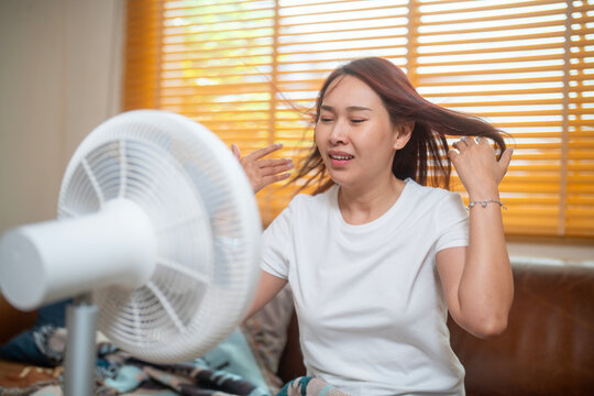 woman tries to cool down with a fan air at home