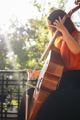 A young woman playing the cello on an outdoor stage