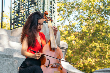 A young woman playing the cello outdoors