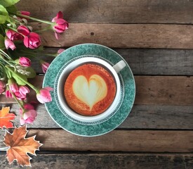 Cup of coffee and flower on wood background 