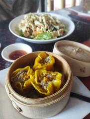 Steamed shumai chinese dumplings in a bamboo steamer, ready to be enjoyed. Vertical
