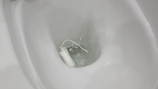 feminine hygiene tampon in toilet bowl absorbs large volumes of fluid, flushing used tampon