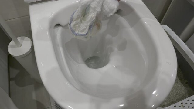 man hand taking out used baby diaper thrown into the toilet