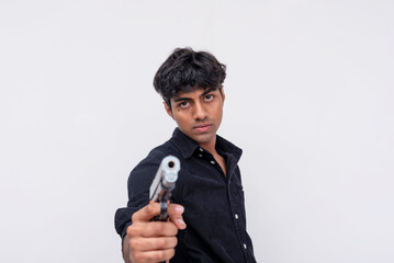 A troubled young teenager aiming a gun at camera on a neutral background