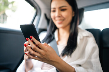 Asian Woman Traveler sitting in car back seats using smartphone call taxi service in application. Online app with cell phone and put on safety belt. Female passenger in car traveling to destination.