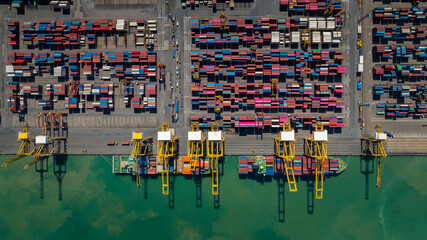 commercial port loading and unloading cargo from container ship import and export by crane for distributing goods by trailers transported to customers and dealers, aerial top view - obrazy, fototapety, plakaty