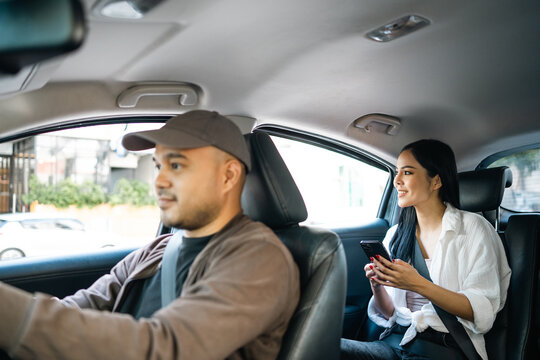 Young asian woman traveler talking with taxi driver explain the route how to travel in direction destination. Passenger showing the direction to taxi driver travel in city. Driver application service