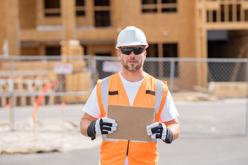 Man Contractor holds piece of empty cardboard sign in his hands. a male construction worker in a helmet stands in a construction zone with empty cardboard. Construction Worker on Duty