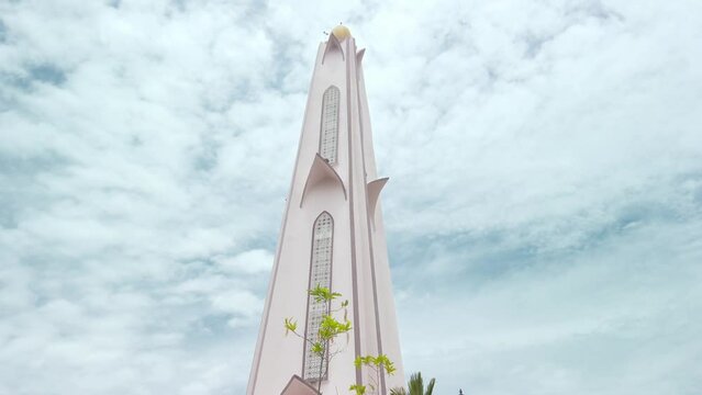 Cinematic low-to-high shot of the minaret of Masjid Selat Melaka in Melaka, Malaysia, during a cloudy day in daylight.