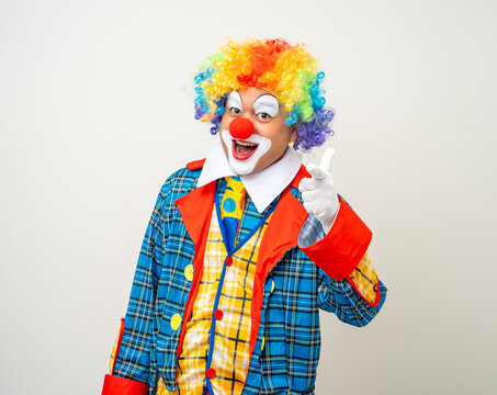 Mr Clown. Portrait of Funny comedian face Clown man in colorful uniform wearing wig standing pointing finger to camera. Happy expression amazed face male bozo in various pose on isolated background.