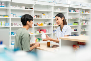 Fototapeta premium Pharmacist recommends medicines to customers.Taking the questions of medication. Asian female pharmacist giving prescription medications to customers at drugstore shelves.