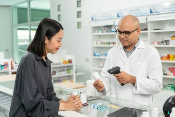 Fotobehang Payment with Barcode scanning to sell medicines. Pharmacist recommends medicines to customers. Professional Asian male pharmacist selling medications to female patient at drugstore shelves. © Chanakon