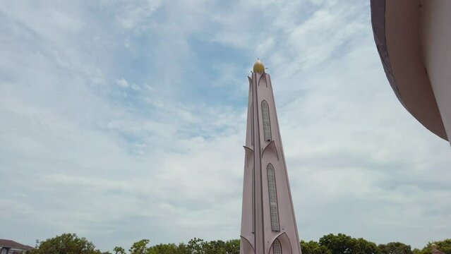 Cinematic low-to-high shot of the minaret of Masjid Selat Melaka in Melaka, Malaysia, during a cloudy day in daylight.