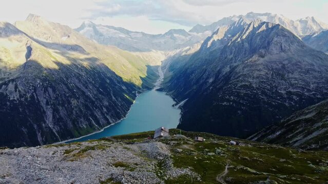 Downward drone shot beautiful scenic view of European hut named "Olpererhütte" in Austrian Alps in summer with the Schlegeis Stausee below