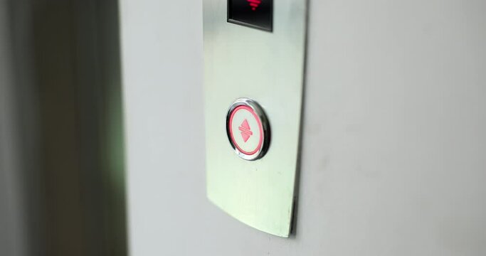 Lady finger presses button to call modern elevator in hallway