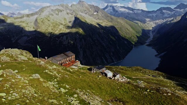 Orbit drone shot beautiful scenic view of European hut named "Olpererh&uuml;tte" in Austrian Alps in summer with the Schlegeis Stausee below