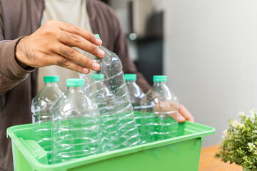 A young man arranged plastic bottles into a box. He assumes plastic bottles will sort of trash before throwing them into the bin. World environment day. Recycle waste reduce environmentally friendly