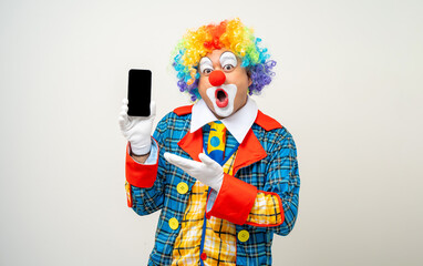 Mr Clown. Portrait of Funny face Clown man in colorful uniform standing holding smartphone. Happy expression male bozo in various pose with cellphone on isolated background.