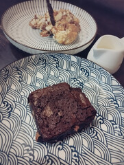 Vertical view of a rich brownie served with a scoop of cream on two separate ceramic plates