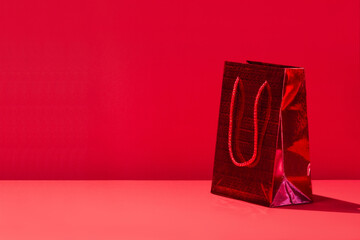 One red gift paper shopping bag on red background. Copy space for text