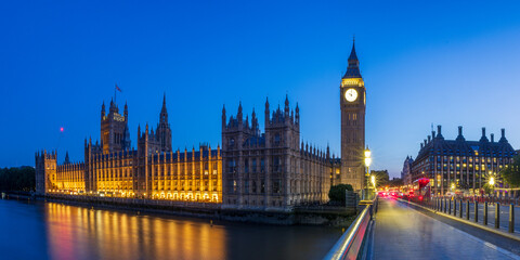 British Houses of Parliament with Big Ben and Westminster bridge just after sunset.