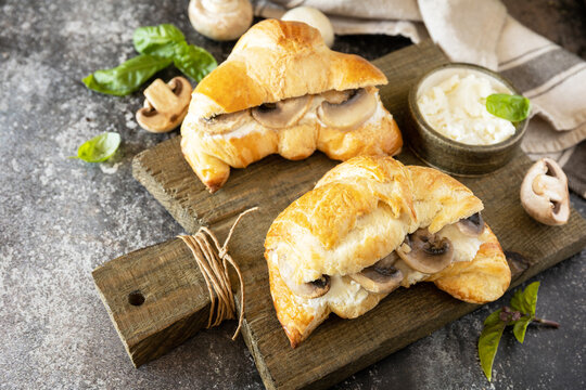 French pastry, tasty freshly baked sandwich. Vegan food style. Croissant with cream cheese and mushroom on a stone background.  Copy space.