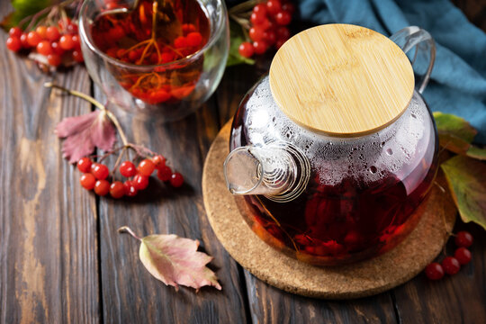 Autumn tea, berry vitamin seasonal drink. Viburnum and cup of healthy viburnum tea on a wood background. Copy space.