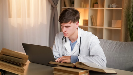 Diagnosis internet research. Study information. Thoughtful doctor man in medical uniform sitting at desk with books scrolling laptop in clinic office interior.