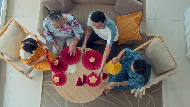 Directly above view of multi-generational Asian family sitting at round table while making decorations for Tet celebration at homeDirectly above view of multi-generational Asian family sitting at roun