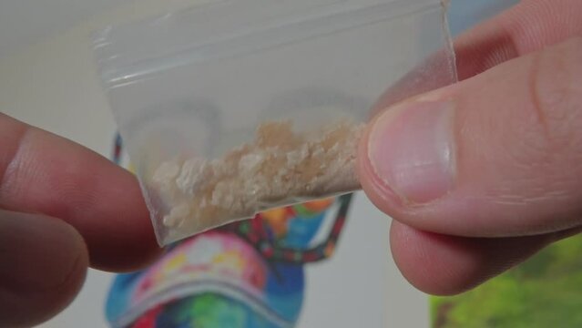 touching transparent bag of methylenedioxymethamphetamine. Drug addict live style