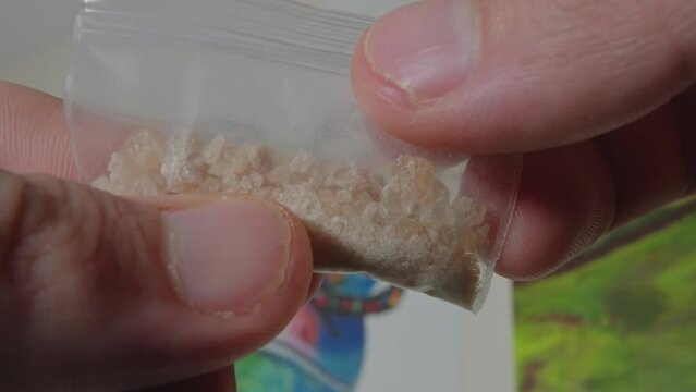 Exploring bag of Molly and fentanyl and taking one crystal. Drug addict life style. MDMA Close up