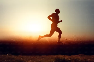 Schilderijen op glas Runner athlete running at sunset. man fitness jogging workout wellness concept © digitalpochi