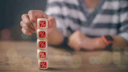 Businesswoman stacking red percentage sign on wooden cube block for financial planning of interest...