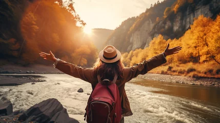 Zelfklevend Fotobehang traveler with backpack relaxing by autumn river at sunset © Aura