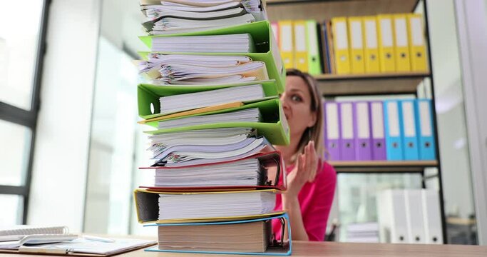 Woman worker surprised by stack of folders to complete
