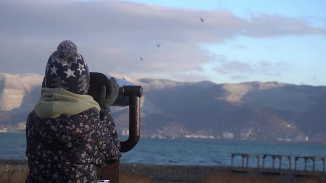Little girl looking through binoculars in mountains. Novorossiysk, Russia