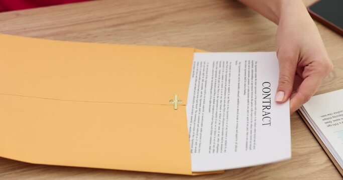 Woman takes contract out of envelope for client to sign