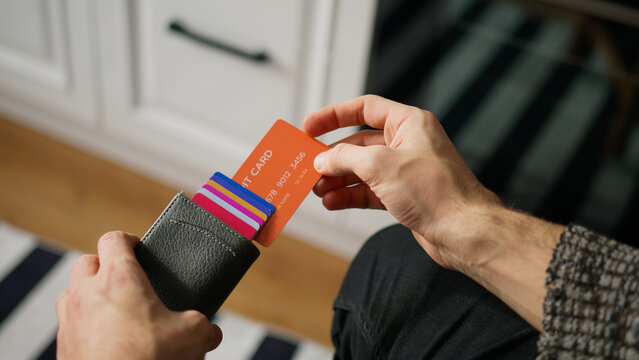 Close-up of young man hand opens card wallet full of credit cards, takes one out	
