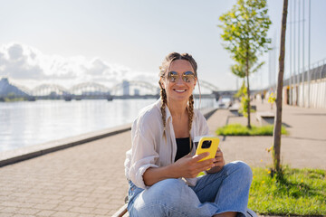 Fototapeta premium Young woman hipster sitting at city street , use cellophane, chatting with friends, have video call