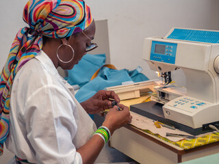close up of adult black seamstress use sewing machine to skillfully sew a shirt with precision care