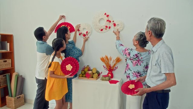 Long shot of happy Asian family decorating white wall while celebrating Lunar New Year together at homeLong shot of happy Asian family decorating white wall while celebrating Lunar New Year together a