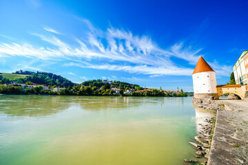 Fototapeta na wymiar View of the Inn River and the Schaiblingsturm in Passau. Historic round tower of the city with the surrounding landscape. Old defense tower. 