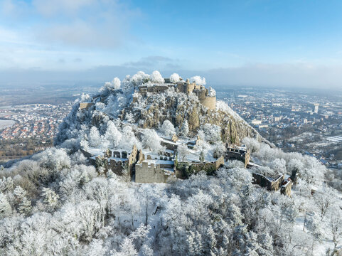 Luftbild vom verschneiten Hegauvulkan Hohentwiel mit Deutschlands gr&ouml;&szlig;ter Burgruine, umgeben von frostigen B&auml;umen in einer Winterlandschaft.