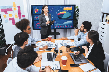 Young asian businesswoman presenting data analysis dashboard on TV screen in modern meeting....