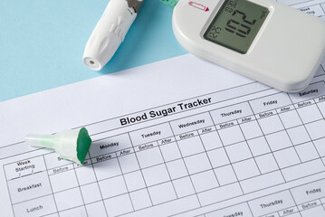 Top view of glucometer, lancet pen, strips and blood sugar tracker on blue background. diabetes...