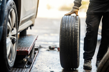 Cropped picture of a vulcanizing worker with car tire in workshop.