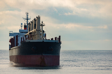 A large cargo sea ship sails on the ocean among the waves