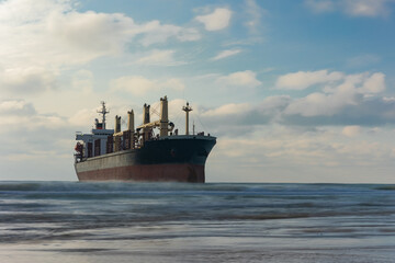 A large cargo sea ship sails on the ocean among the waves