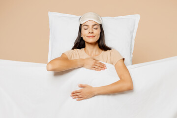 Young calm pregnant Latin woman wears pyjamas jam sleep eye mask rest relax at home under duvet...