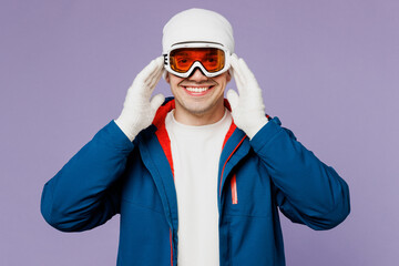 Skier smiling happy cheerful man wear warm blue windbreaker jacket touch ski goggles mask hat...